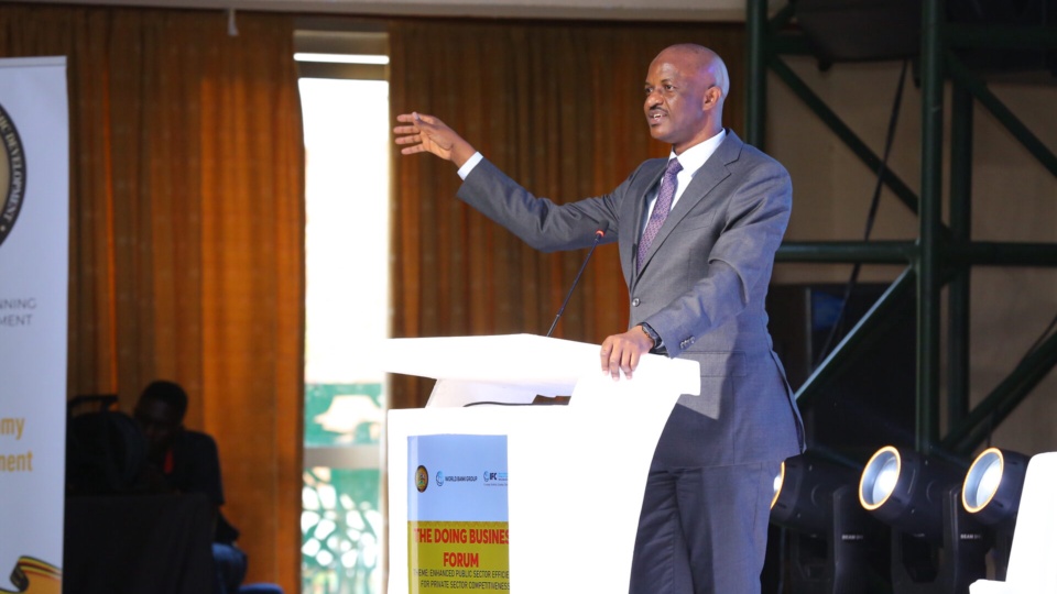 The Permanent Secretary / Secretary to the Treasury addressing the Forum from the lectern, which carries the Forum theme.