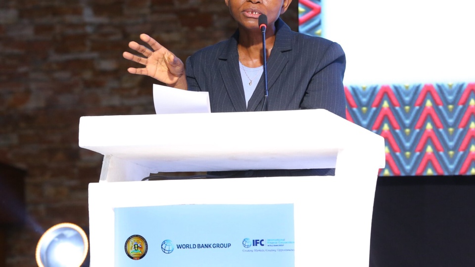 A speaker addressing the Forum from the lectern in front of a screen showing partner logos.