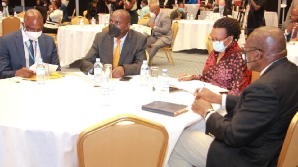 Delegates in face masks seated around a table at the 12th National Competitiveness Forum.